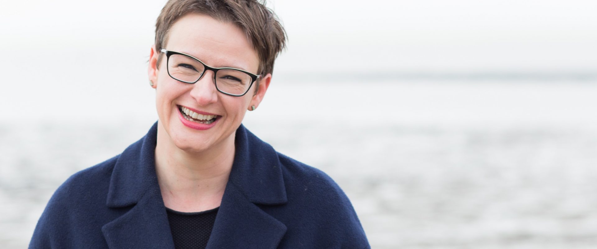 Pisarka Katherine May, autorka książki "Zimowanie. Moc odpoczynku i wyciszenia, kiedy wszystko idzie nie tak". Portret nad brzegiem morza zimą. Fot. © Sara Norling