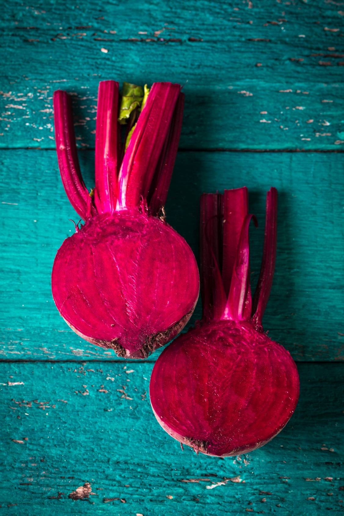 Sok z buraka dla sportowców. Jak zrobić sok z buraka? Połówki buraka na niebieskim tle.