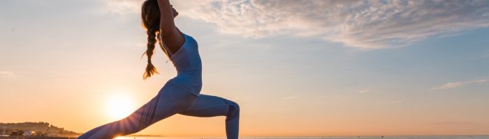 Joga klasyczna Ashtanga joga- na czym polega ośmiostopniowa ścieżka jogi. Kobieta ćwiczy jogę o zachodzie słońca na plaży.