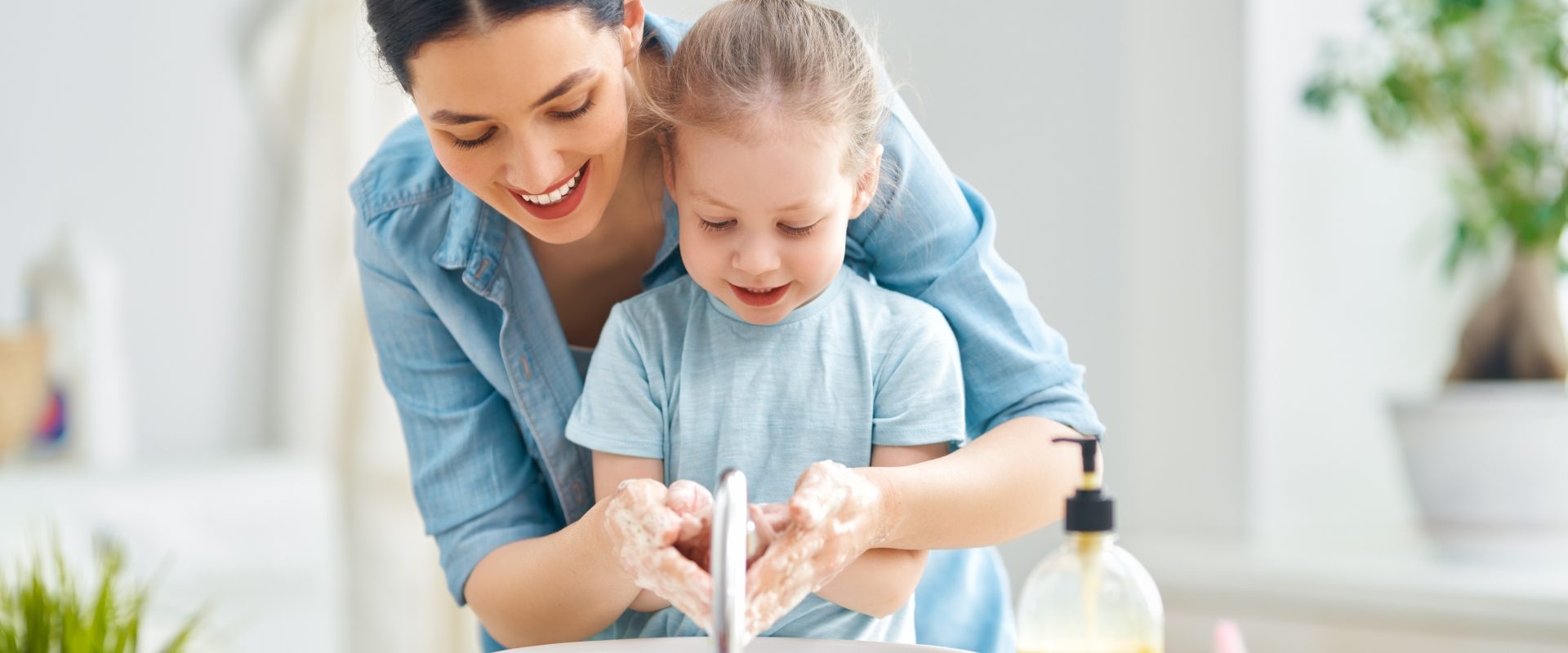 Aby zapobiec rozprzestrzenianiu się koronawirusa trzeba często myć ręce. Jak zadbać o przesuszone dłonie? Jakie są najlepsze domowe sposoby na suche dłonie? Mama uczy córkę jak myć ręce.