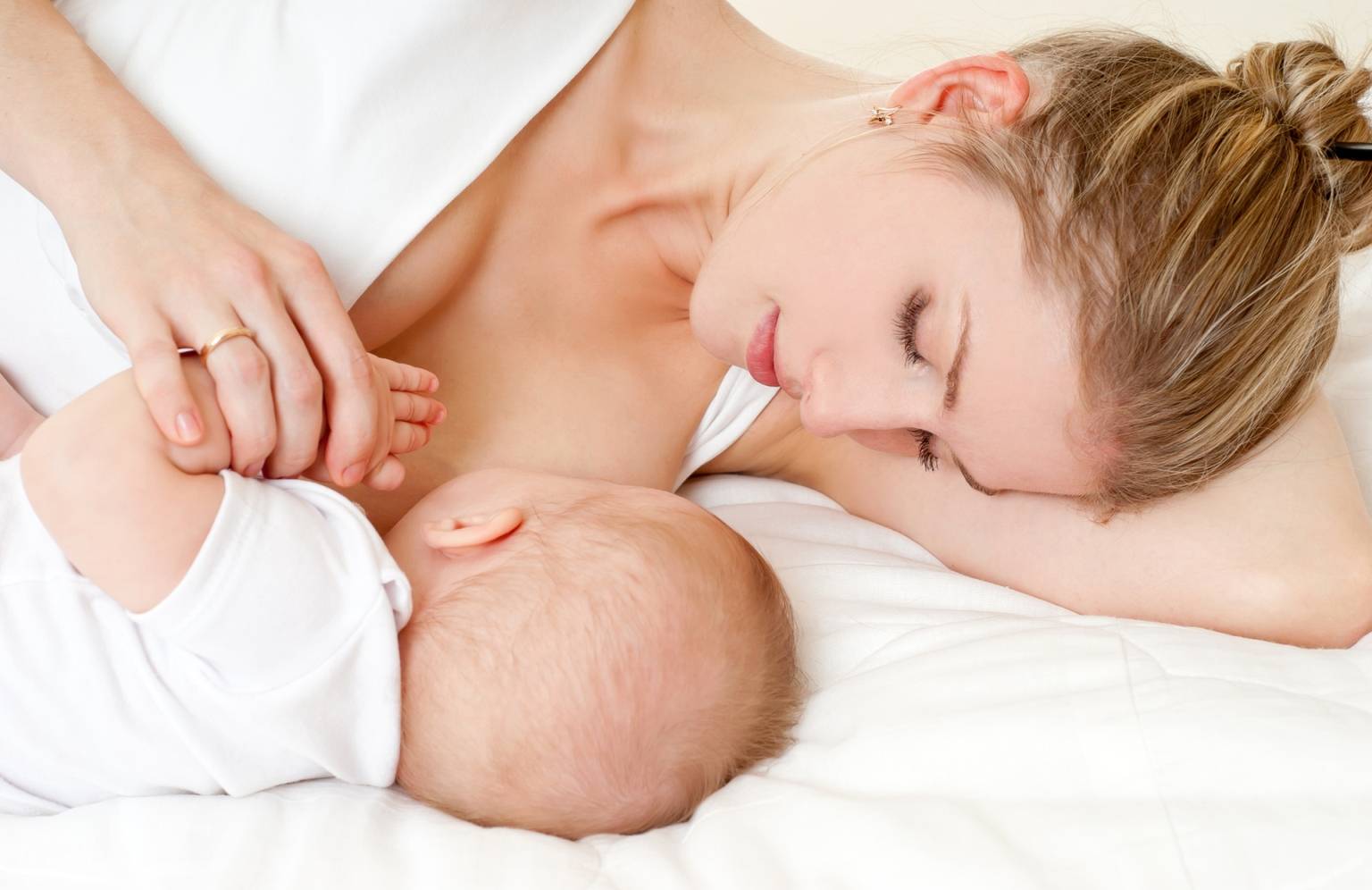 Zastój pokarmu w piersiach - jak leczyć? Kobieta karmi piersią niemowlaka.