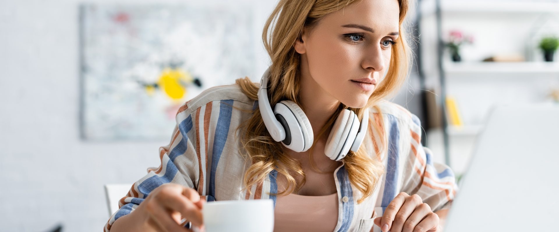 Problemy z koncentracją - jak poprawić zdolność skupienia uwagi? Młoda kobieta siedzi z kubkiem kawy przy komputerze.