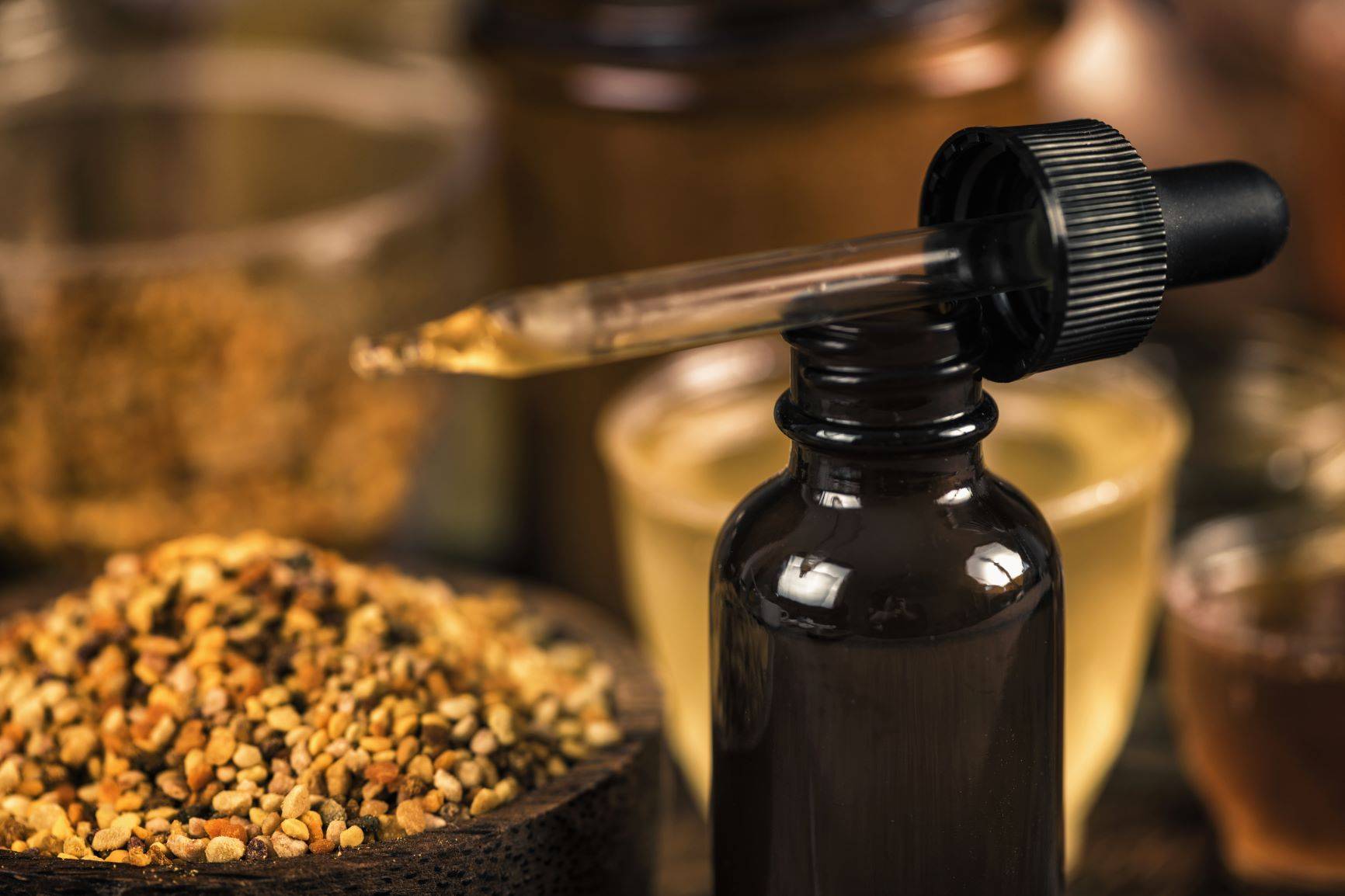 Propolis - lek na glejaka mózgu. Wyciąg z propolisu w brązowej buteleczce, obok propolis w drewnianej miseczce.