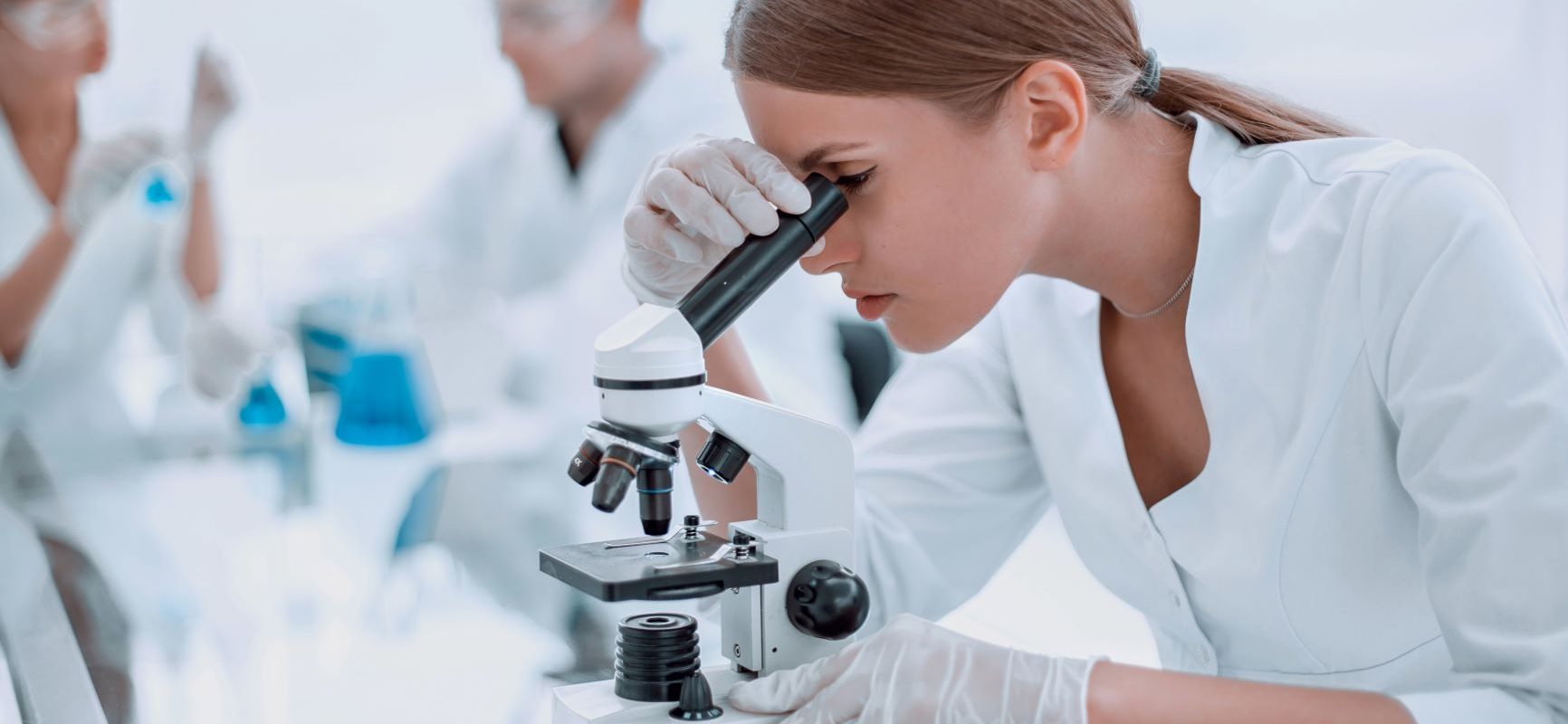 Przeszczep kału - w czym może pomóc? Laborantka bada próbki pod mikroskopem w laboratorium.