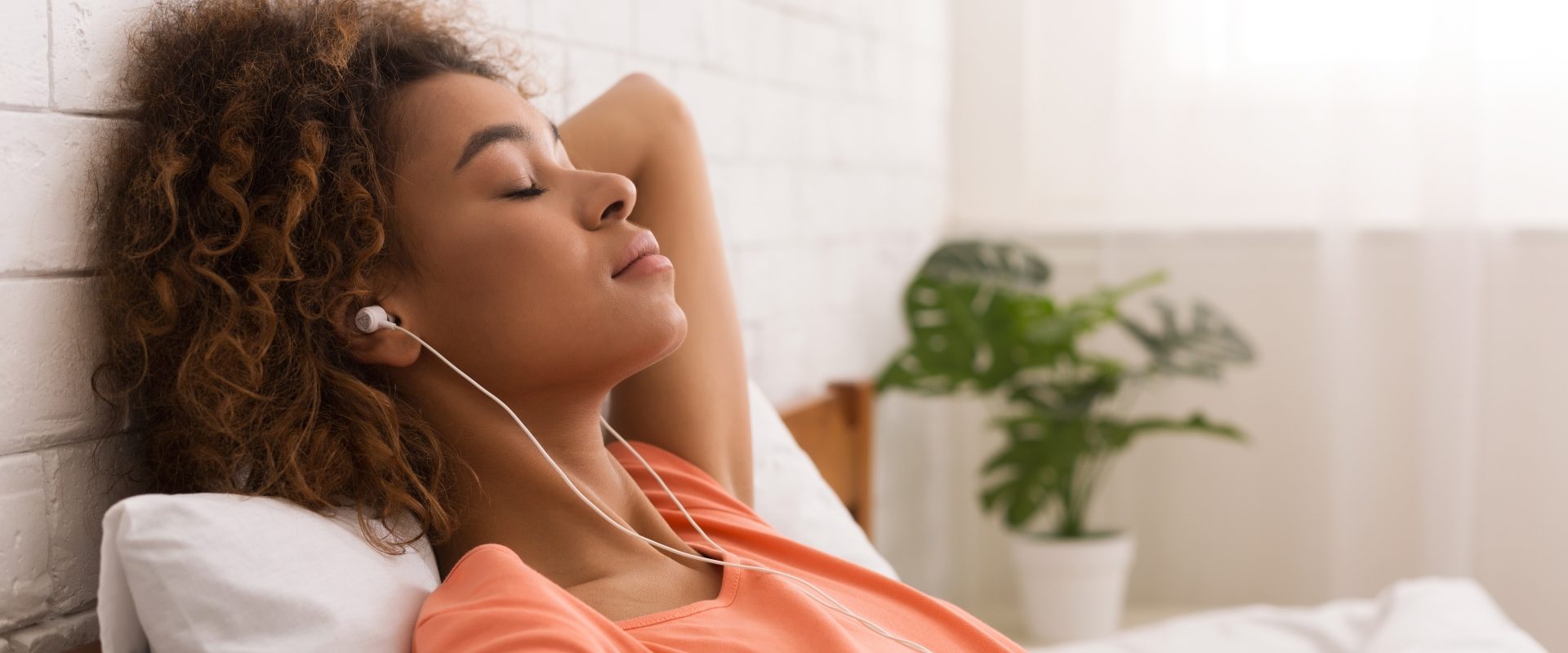 Trening autogenny Schultza - na czym polega? Kobieta relaksuje się w domu ze słuchawkami w uszach.