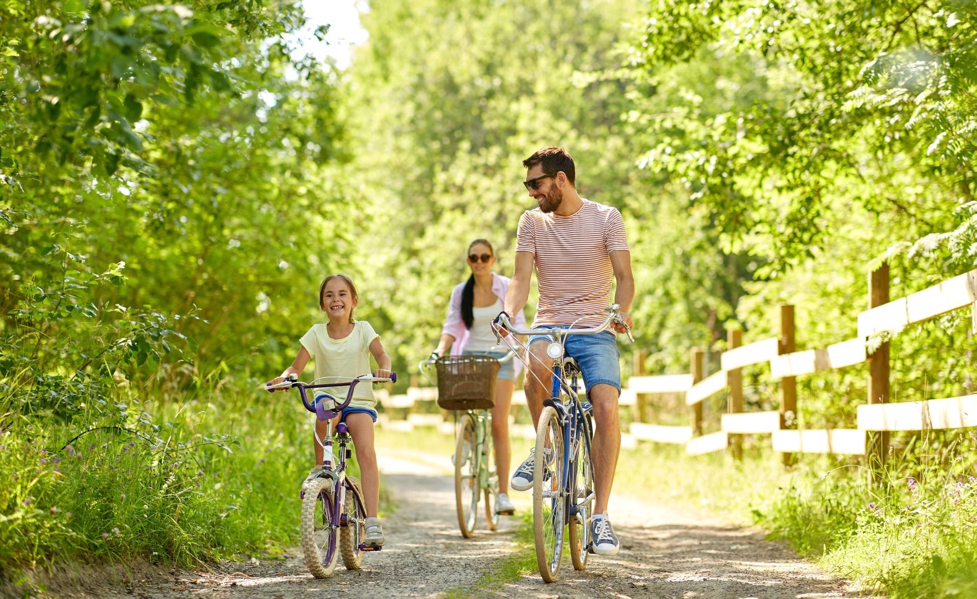 Reumatyzm - jak mu zapobiec? Szczęśliwa rodzina - mama, tata i córka - jadą na rowerach przez las.