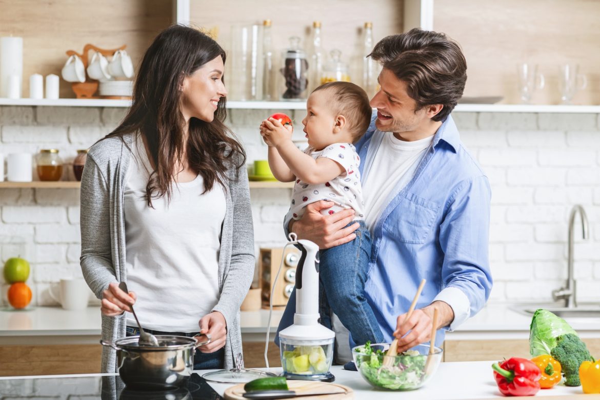Zdrowe jelita to dobra odporność. Jak dbać o florę bakteryjną? Szczęśliwa rodzina - mama, tata i dziecko - przygotowuje zdrowy posiłek w kuchni.