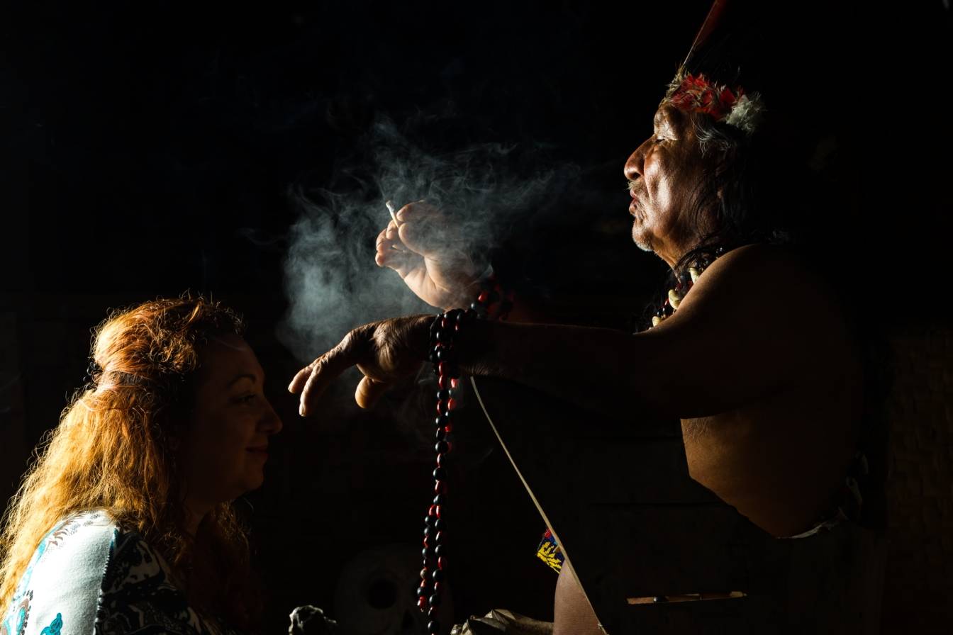Szaman rozpoczyna rytuał ayahuasca w Ekwadorze. Klęczy przed nim uczestniczka ceremonii.