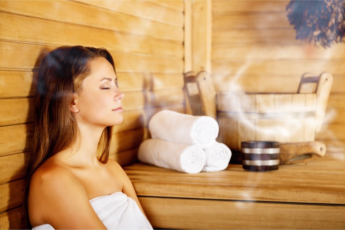 Sauna wspiera odporność. Jak korzystać z sauny? Kobieta w białym ręczniku relaksuje się w saunie suchej w SPA.