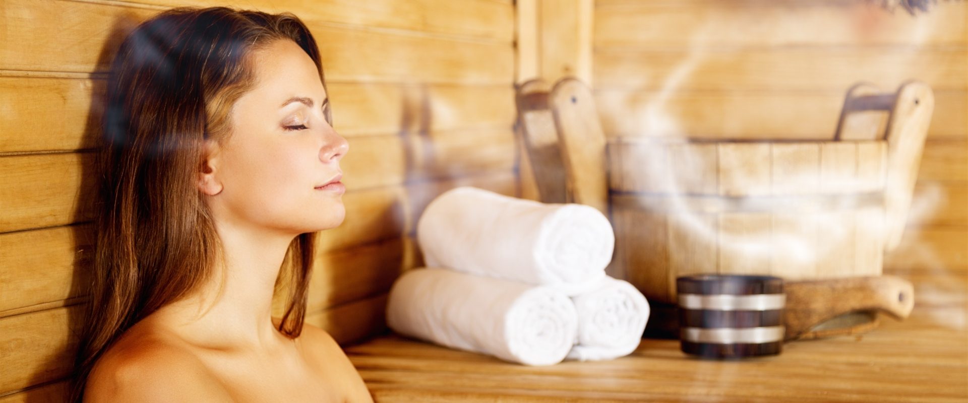 Sauna wspiera odporność. Jak korzystać z sauny? Kobieta w białym ręczniku relaksuje się w saunie suchej w SPA.