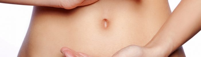 SIBO - zespół rozrostu bakteryjnego w jelicie cienkim - przyczyny, objawy, leczenie. Zbliżenie na kobiecy brzuch.