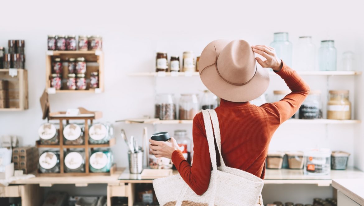 Jak żyć w duchu zero waste? Kobieta w eko sklepie wybiera produkty pochodzące ze zrównoważonego rozwoju.