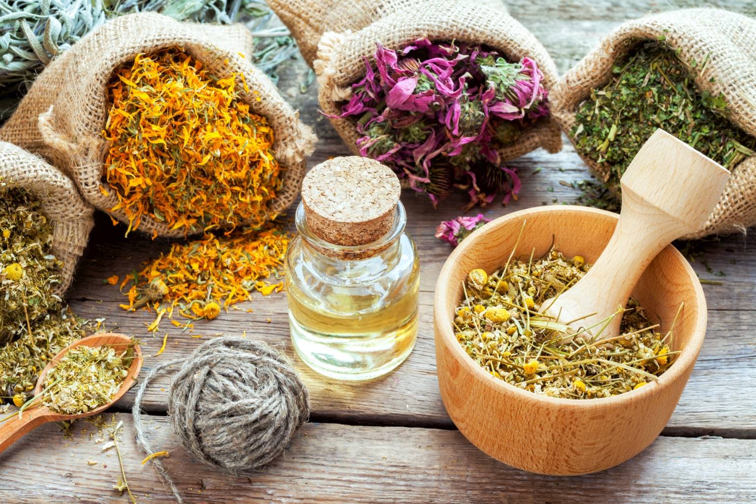 Roślinne leki na prostatę - jakie łagodzą objawy? Suszone zioła i rośliny lecznicze w płóciennych woreczkach i moździerzu.