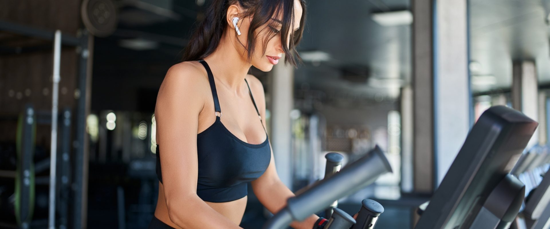 Trening 36 minut - na czym polega? Kobieta w stroju sportowym ćwiczy na orbitreku na siłowni.