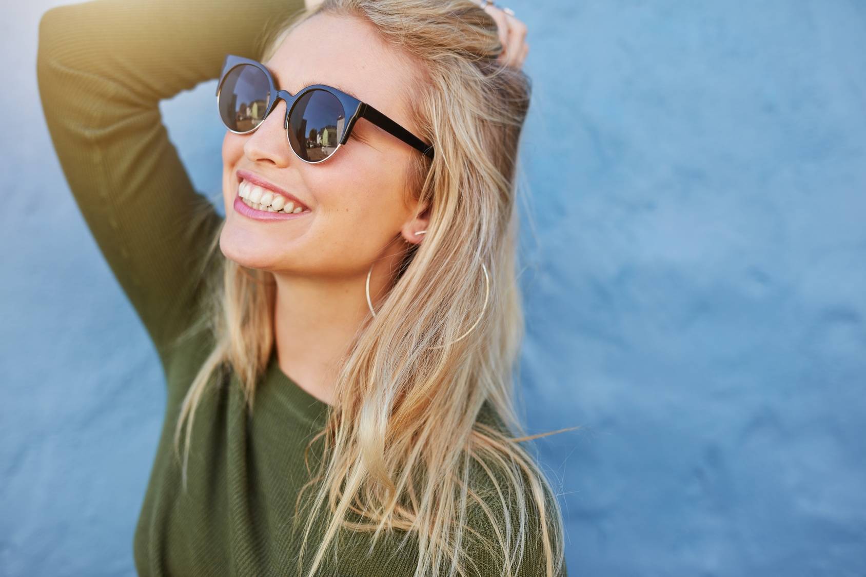 Sirtuiny - eliksir młodości, białka odpowiedzialne za długowieczność i szczupłą sylwetkę. Czym jest dieta sirt (sirtfood)? Uśmiechnięta kobieta w okularach przeciwsłonecznych.