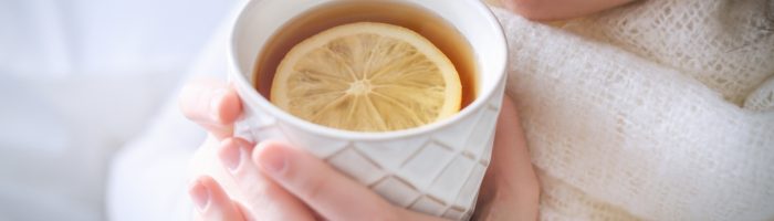 Dlaczego lepiej nie pić herbaty z cytryną i nie suplementować witaminy C w trakcie przeziębienia? Wytłumaczy to medycyna chińska. Przeziębiona kobieta pije herbatę z cytryną w białym kubku.