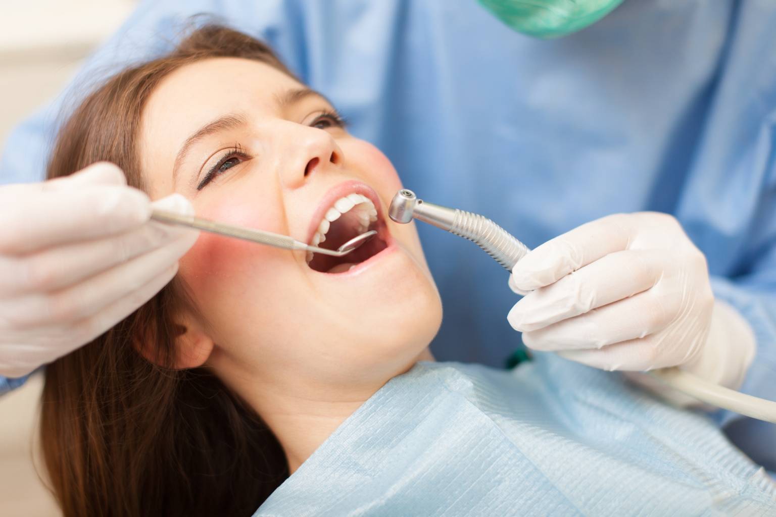 Jak prawidłowo dbać o higienę jamy ustnej? Młoda kobieta na wizycie u stomatologa, siedzi na fotelu dentystycznym.