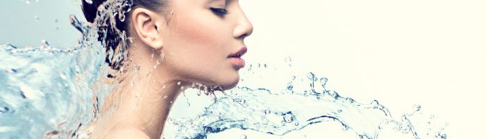 Hydroterapia - na czym polegają kuracje wodne i hartowanie wodą? Kobieta w strumieniach wody.
