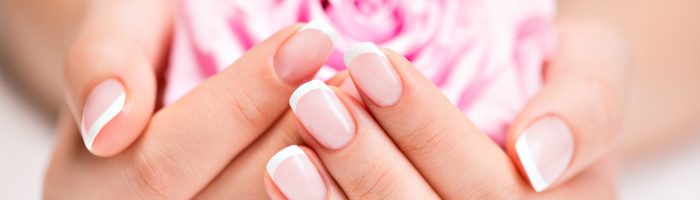 O czym świadczy wygląd paznokci? Jak powinny wyglądać zdrowe paznokcie? Dieta na zdrowe i mocne paznokcie. Kobieta trzyma w zadbanych dłoniach kwiat róży.