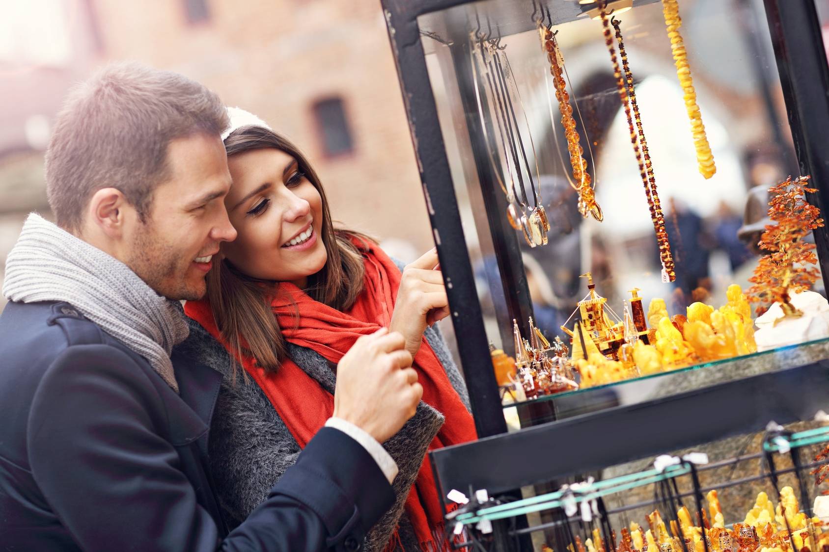 Bursztyn - kamień szlachetny na biżuterię. Jak rozpoznać bursztyn? Para przygląda się wystawie z biżuterią z bursztynów na gdańskiej Starówce.