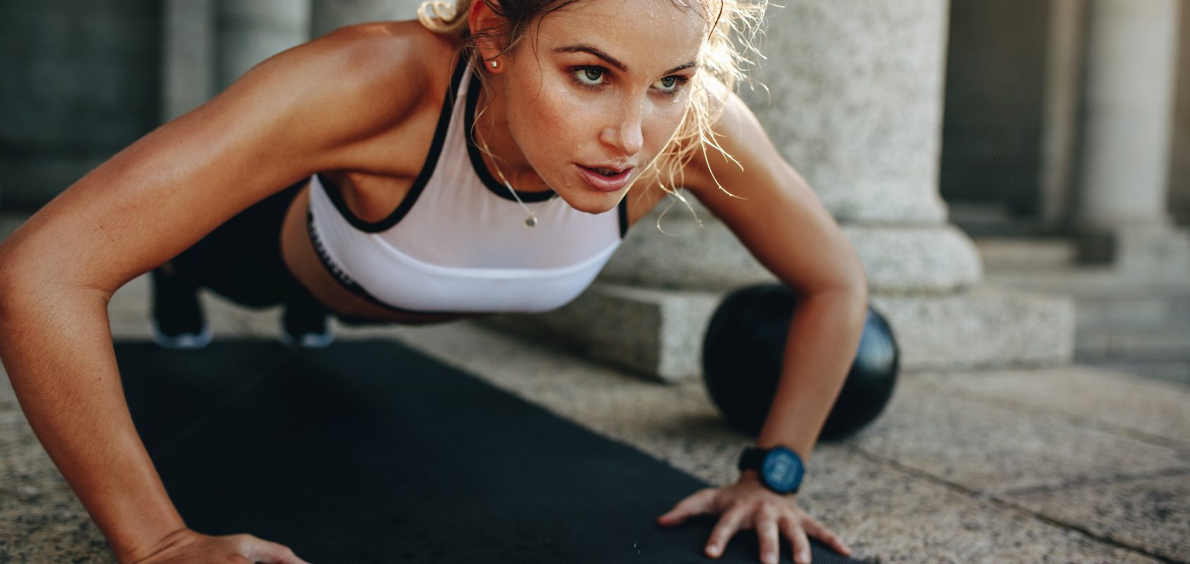 Ból głowy po wysiłku - jaka może być jego przyczyna? Kobieta trenuje na siłowni.