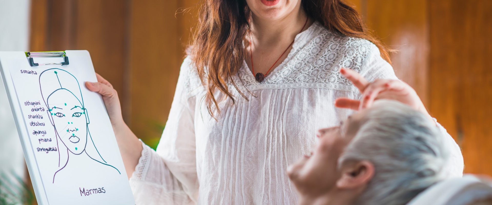 Punkty marma - na czym polega terapia punktów marma? Terapeutka ajurwedy pokazuje pacjentce jak będzie przebiegać terapia.