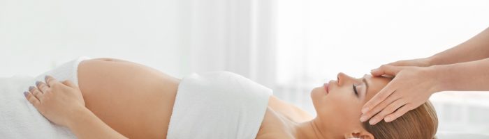 Medycyna chińska na dolegliwości w ciąży. Kobieta w ciąży podczas zabiegu akupunktury.