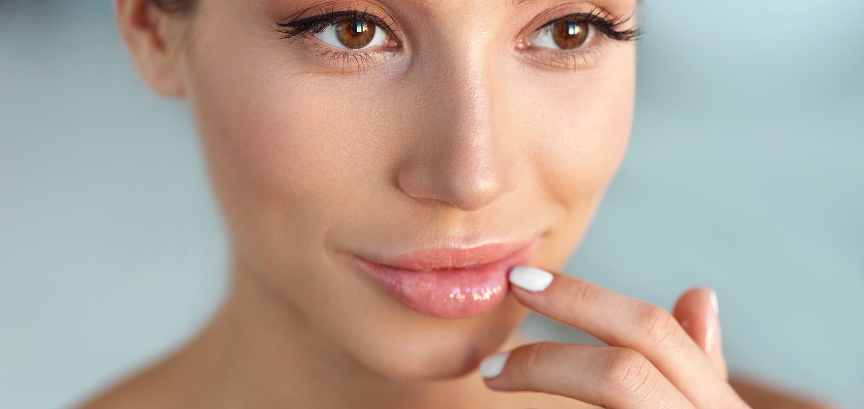 Jak leczyć zajady? Domowe sposoby na zajady. Kobieta dotyka palcem swoich warg.