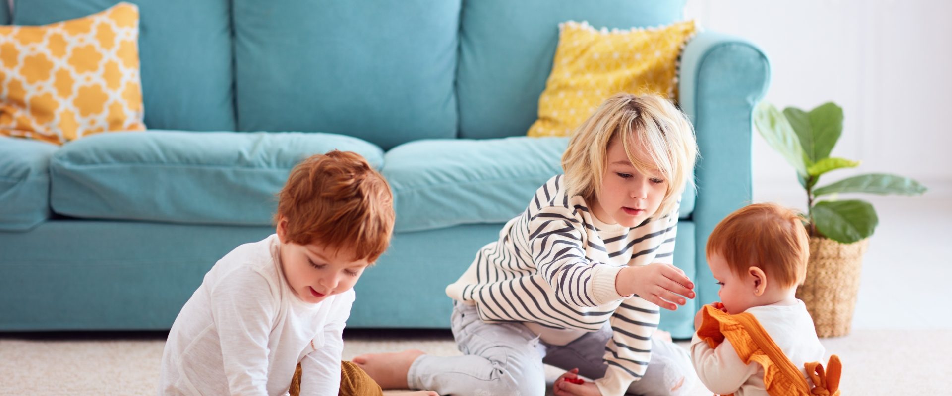 Jak wykonać resuscytację niemowlaka? Jak przebiega RKO u niemowląt krok po kroku? Starsze dzieci bawią się klockami z niemowlakiem w domu.