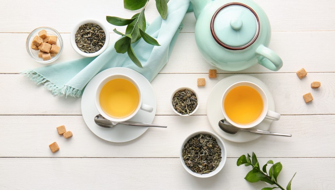 Zielona herbata w błękitnym imbryczku i filiżankach na białych deskach. Dlaczego warto pić zieloną herbatę?