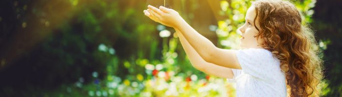 Zielona jak drzewo - wiosenne przebudzenie. Jak żyć w zgodzie z naturą i porami roku, aby mieć dobre samopoczucie? Co zaleca na wiosnę medycyna chińska? Dziewczynka stoi w lesie, trzyma młode drzewko i wznosi je ku słońcu.